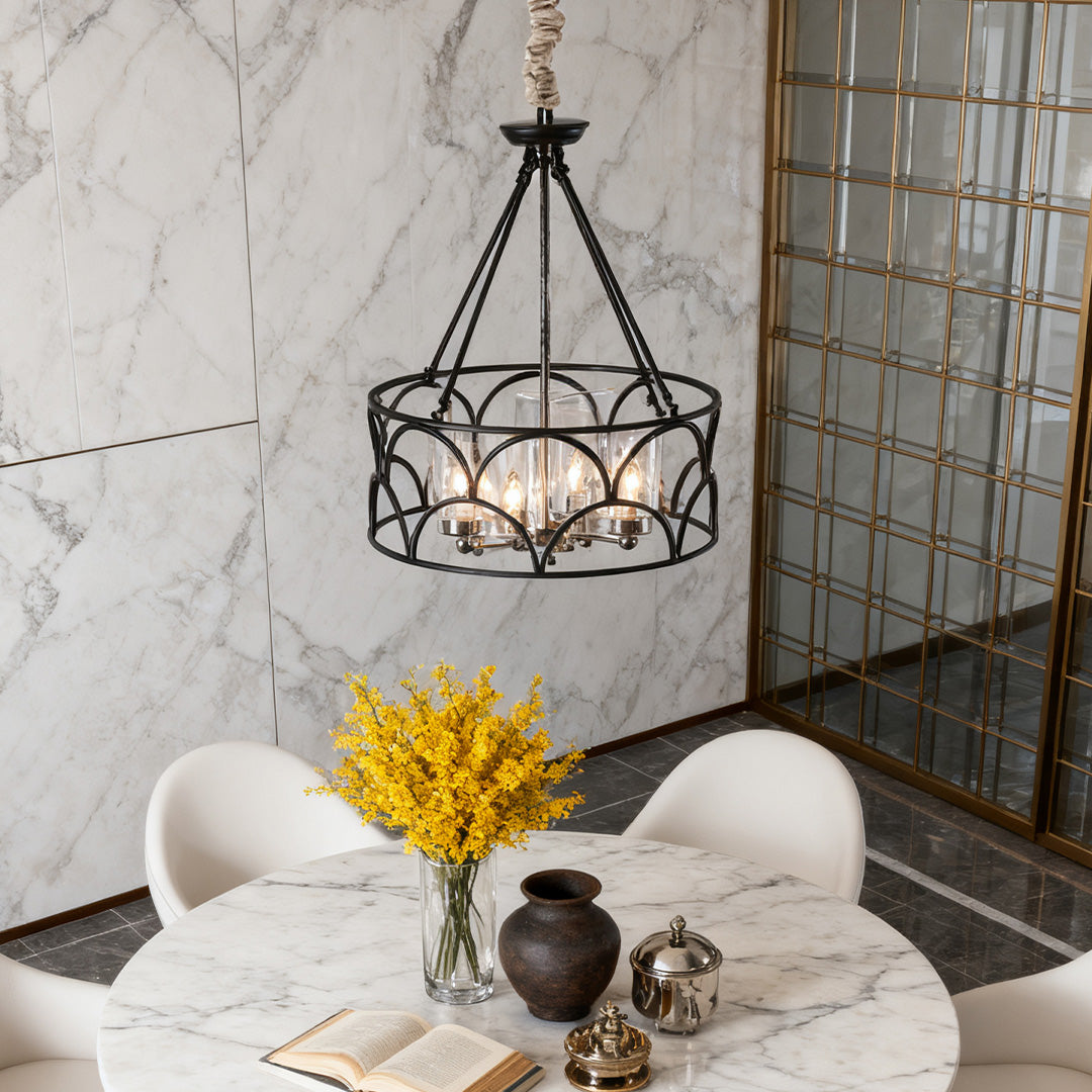 Chic chandelier with black geometric cage and light-catching crystals, centered above a round white table in a room with marble features.