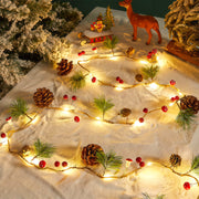 Christmas LED string lights displayed on a snow-like surface with pinecones and warm white glow.
