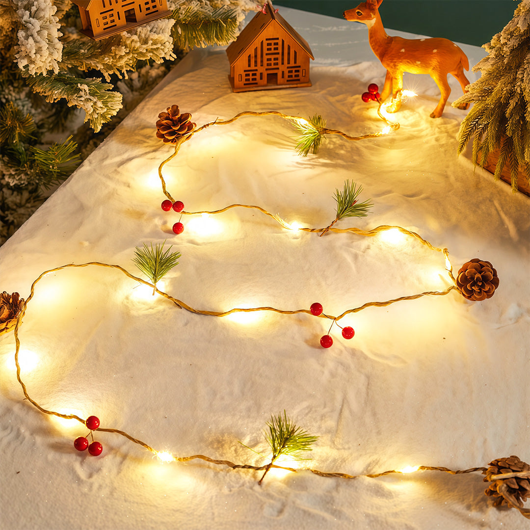 Warm white Christmas LED string lights set on a snowy scene with pinecones and miniature Christmas house.