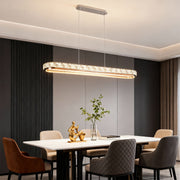 Chrome pendant light installed in a modern dining room with a white table, providing warm and inviting illumination.