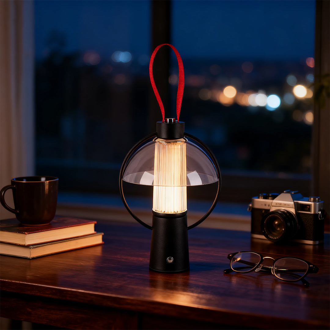 Circle table lamp with red handle providing ambient light on a rustic indoor desk with books and a vintage camera. 