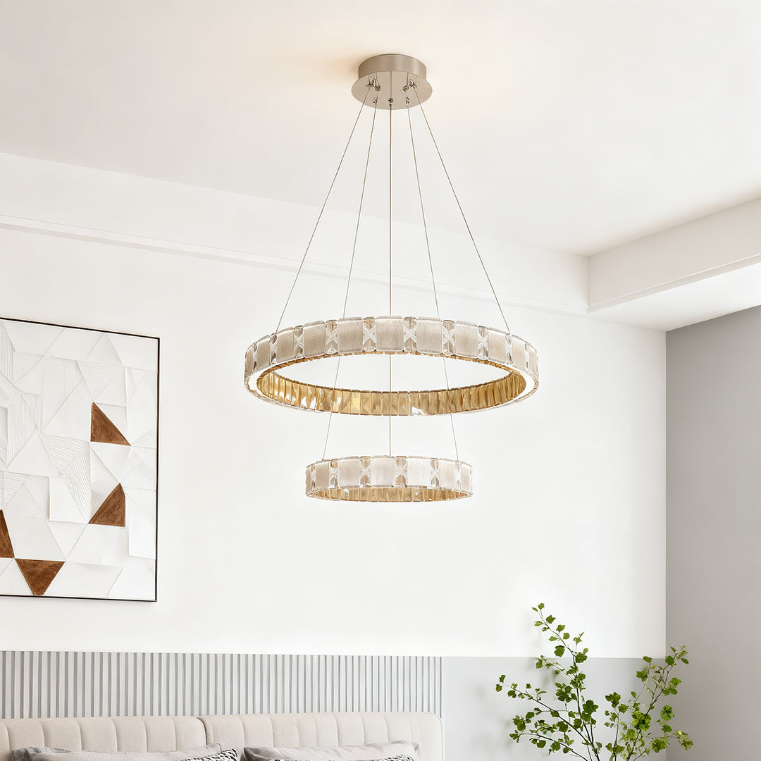Circular chrome chandelier suspended in minimalist white interior with pendant cable design