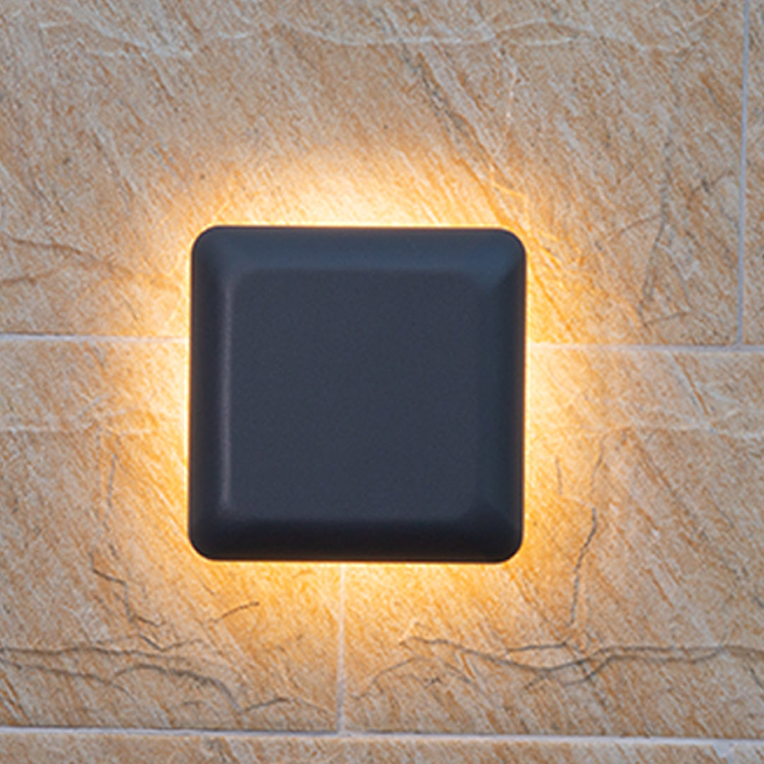 Circular waterproof outdoor wall light with black center creating golden ring glow on stone