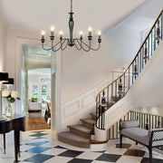 Classic black candle chandelier in elegant foyer with checkered marble floor and grand staircase