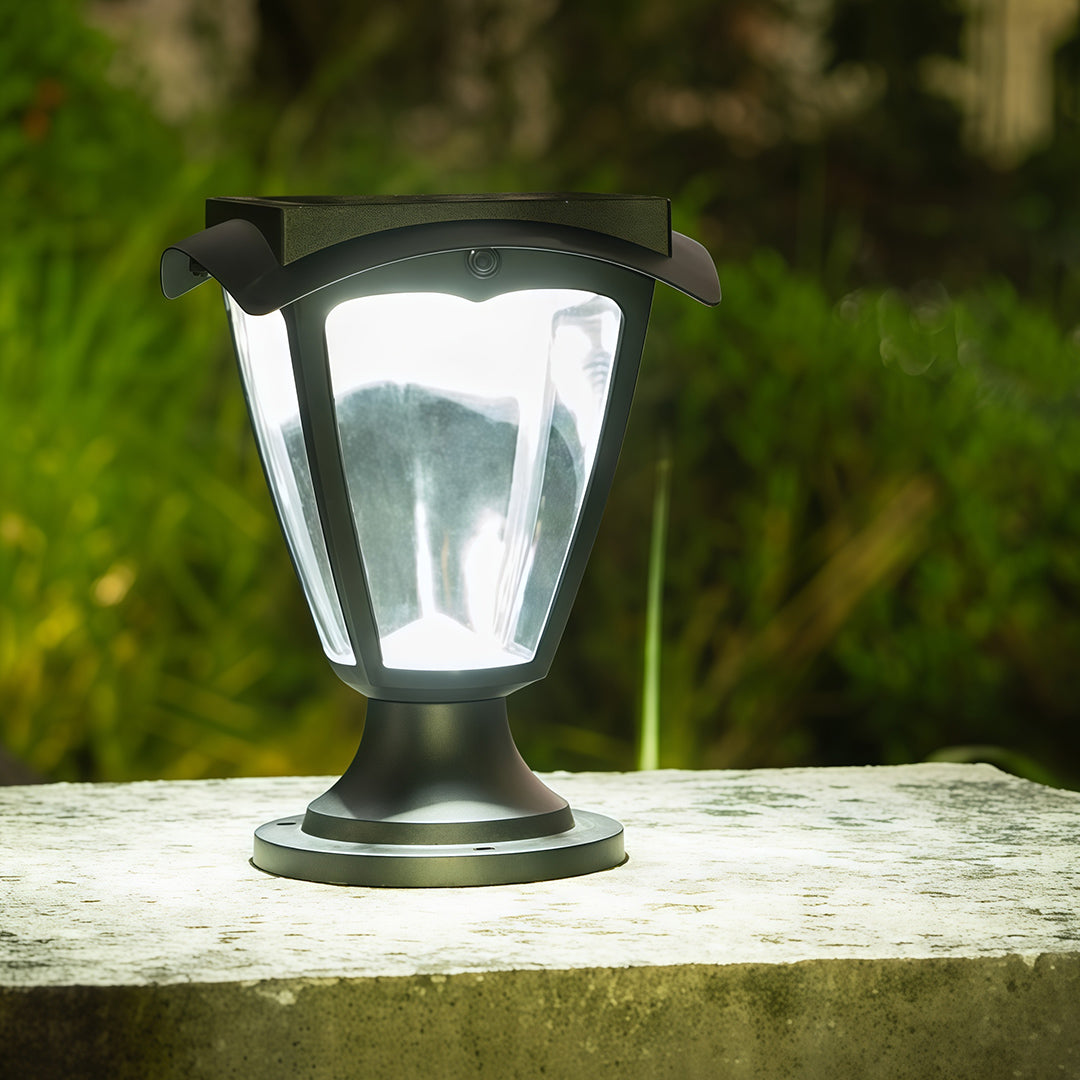 Classic black solar light pillar lantern shown during the day on a stone garden wall.