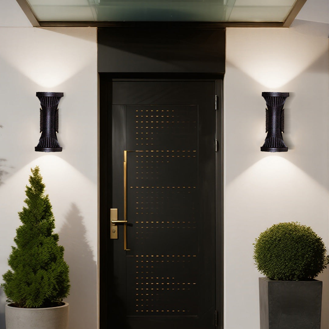 Two classic black up-down Outdoor Wall Lighting Fixtures illuminating the main entrance and potted plants.