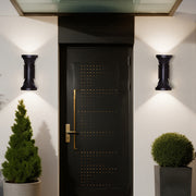 Two classic black up-down Outdoor Wall Lighting Fixtures illuminating the main entrance and potted plants.