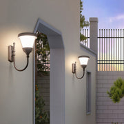 Classic black outdoor wall light mounted along a modern stone wall, lighting up the yard space.