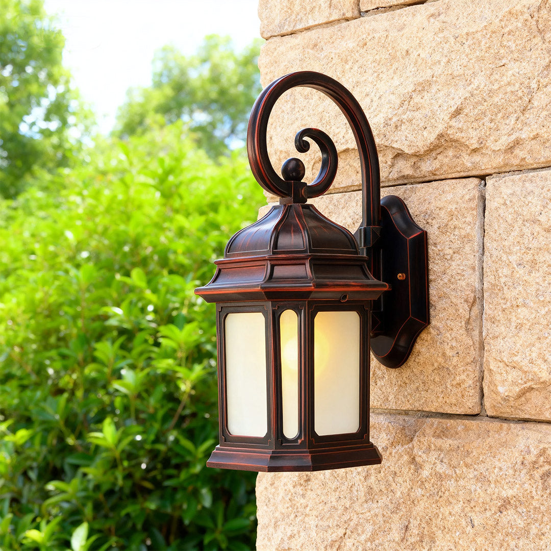 Classic exterior LED wall light mounted on rough textured stone wall beside lush green landscaping