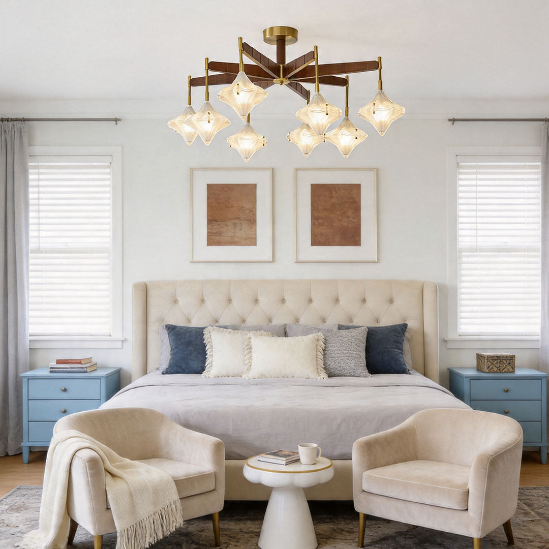 Classic gold chandelier with geometric glass shades hanging above a bed in a bright, elegant bedroom.