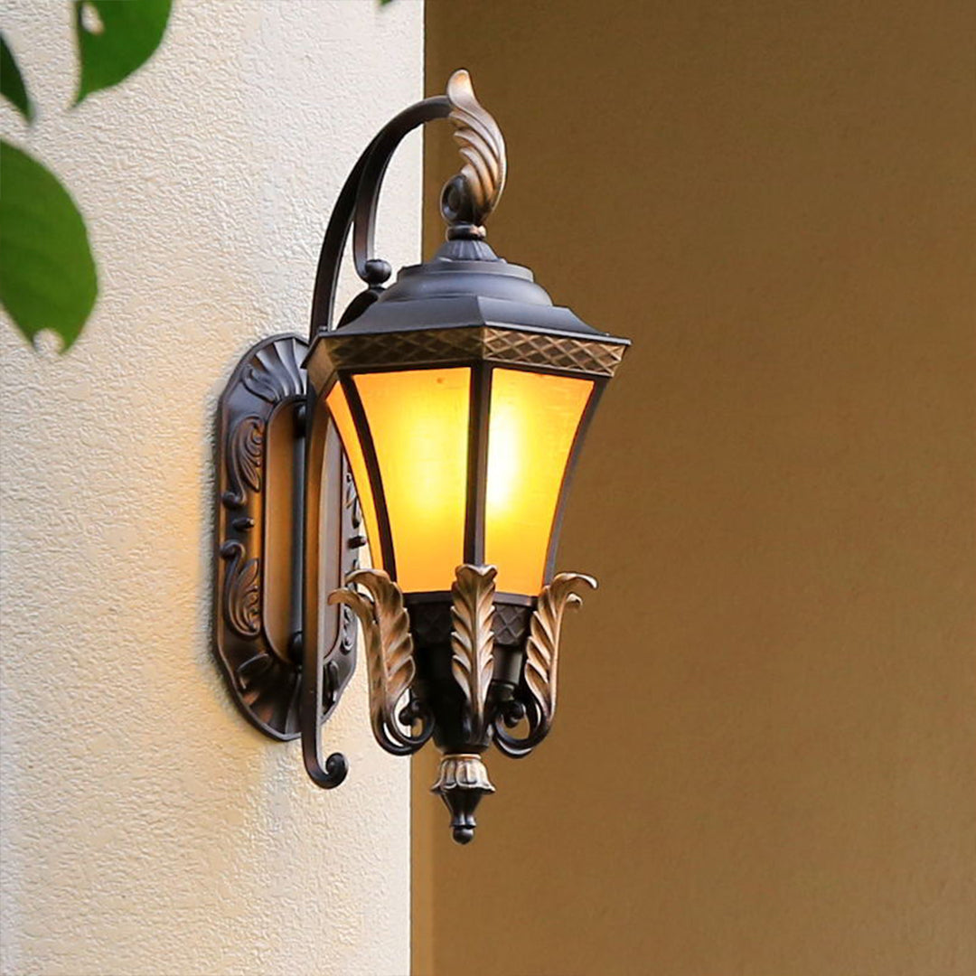 Classic outdoor lantern with scrolled ironwork and amber glass shade mounted on exterior wall for timeless lighting appeal