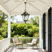 Classic outdoor porch pendant light brightening white covered deck with railing and outdoor furniture