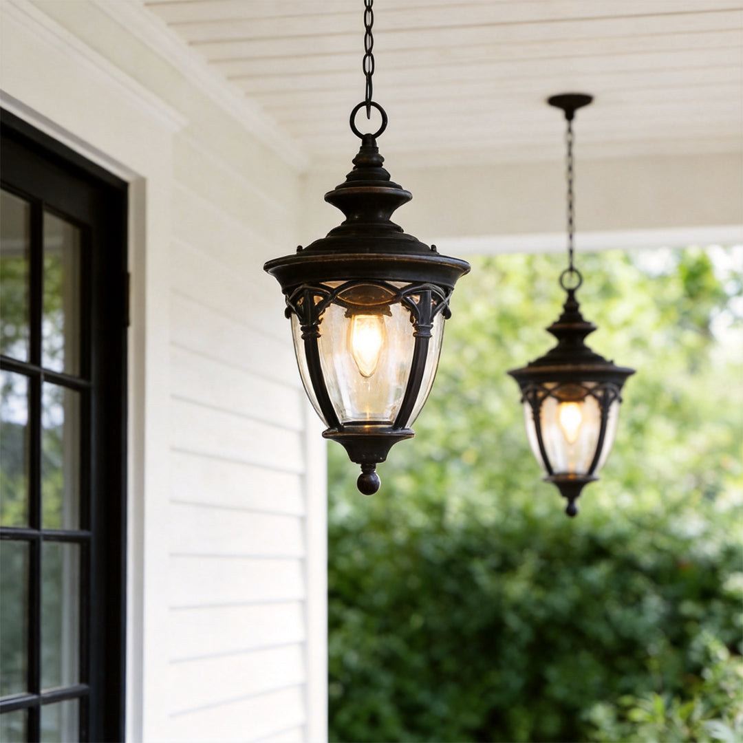 Classic pendant porch light hanging from a white porch ceiling beside black framed windows in a modern farmhouse setting.