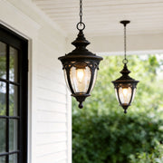 Classic pendant porch light hanging from a white porch ceiling beside black framed windows in a modern farmhouse setting.