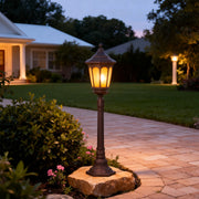 Classic post path light glowing warmly on brick paver driveway near home entrance at evening