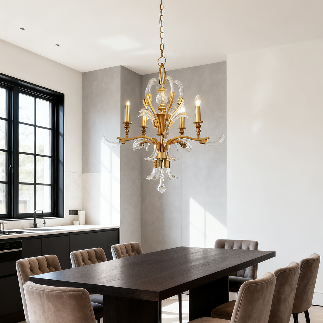 Classic gold and crystal chandelier with six arms and a central crystal sphere, hanging over a large dark wood table in a high-ceiling modern room.