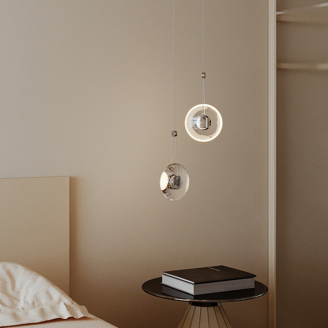 Two clear pendant lights hanging beside a bed, adding a cozy modern touch.