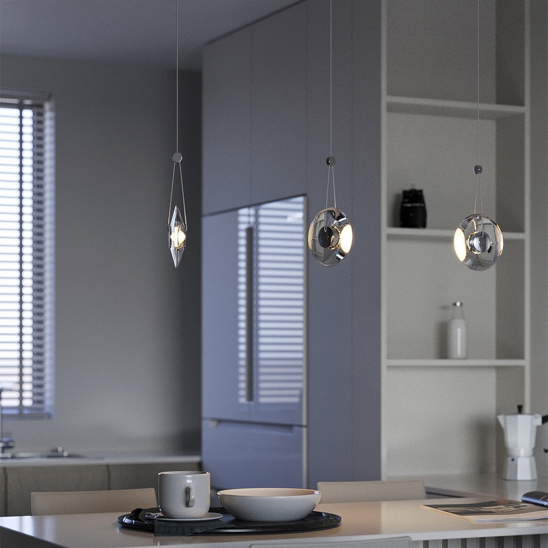 Modern clear pendant lights suspended over a dining table in a minimalist kitchen.