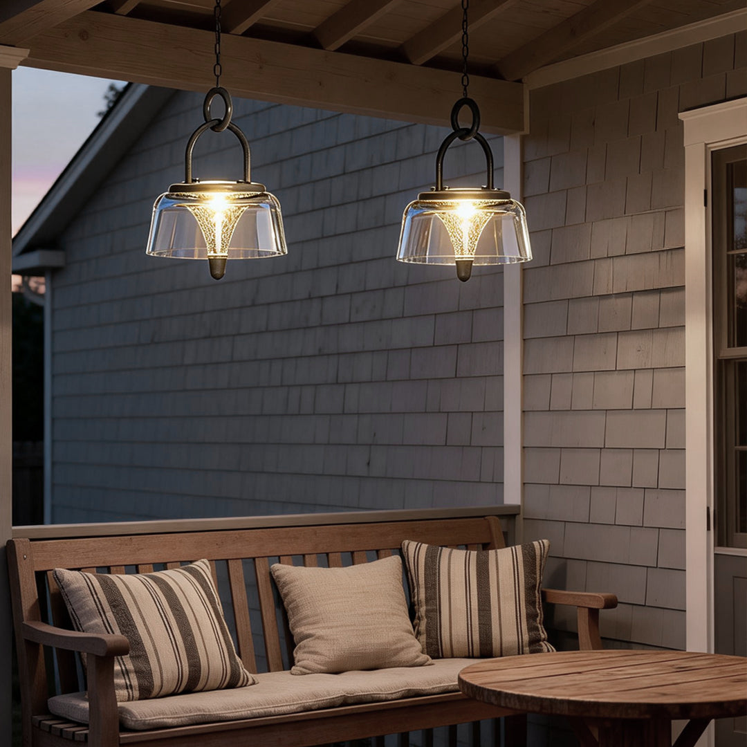 Clear pendant light hanging near a curtain, casting a gentle glow for a cozy outdoor setting.