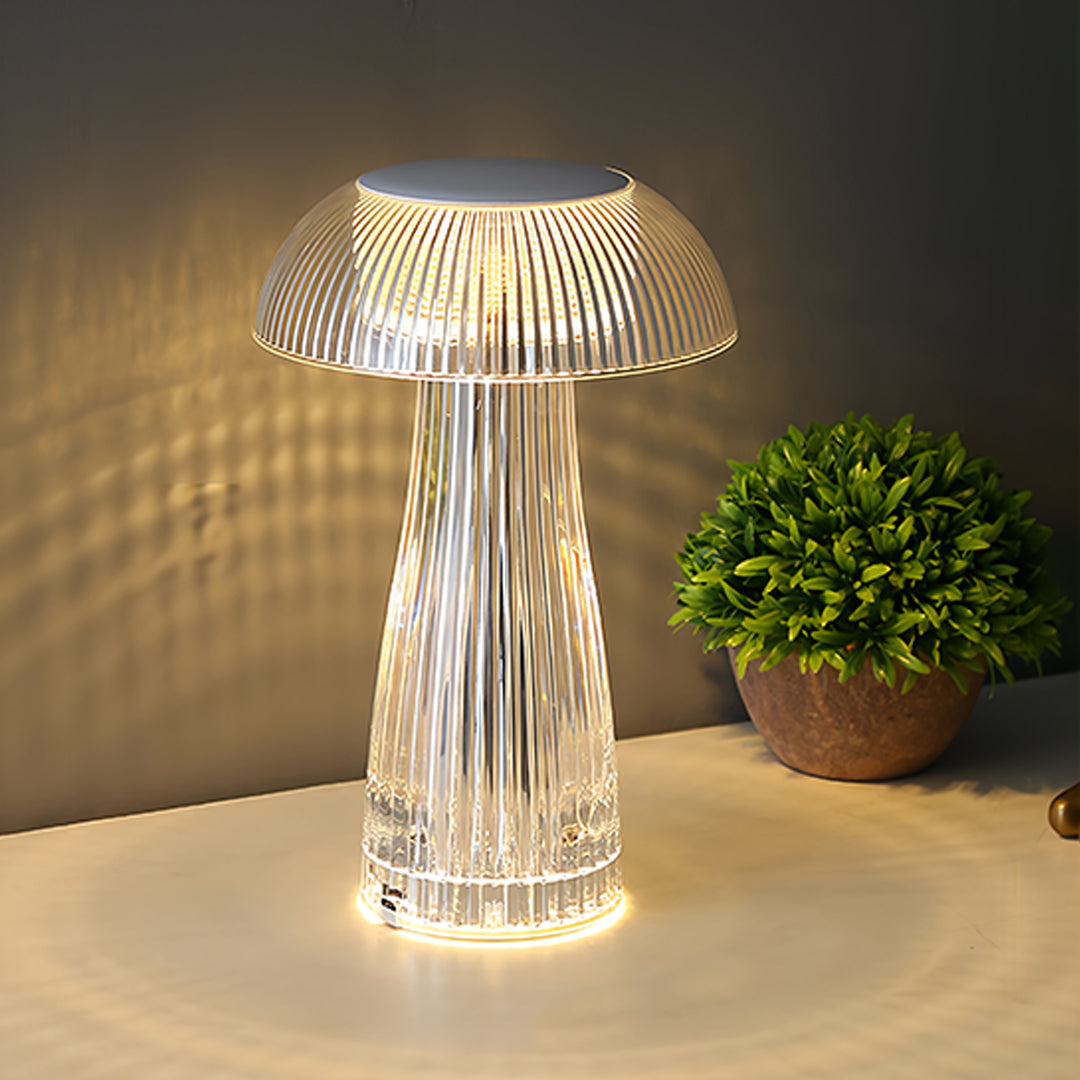 Stylish clear table lamp glowing warmly next to decorative plant in modern setting
