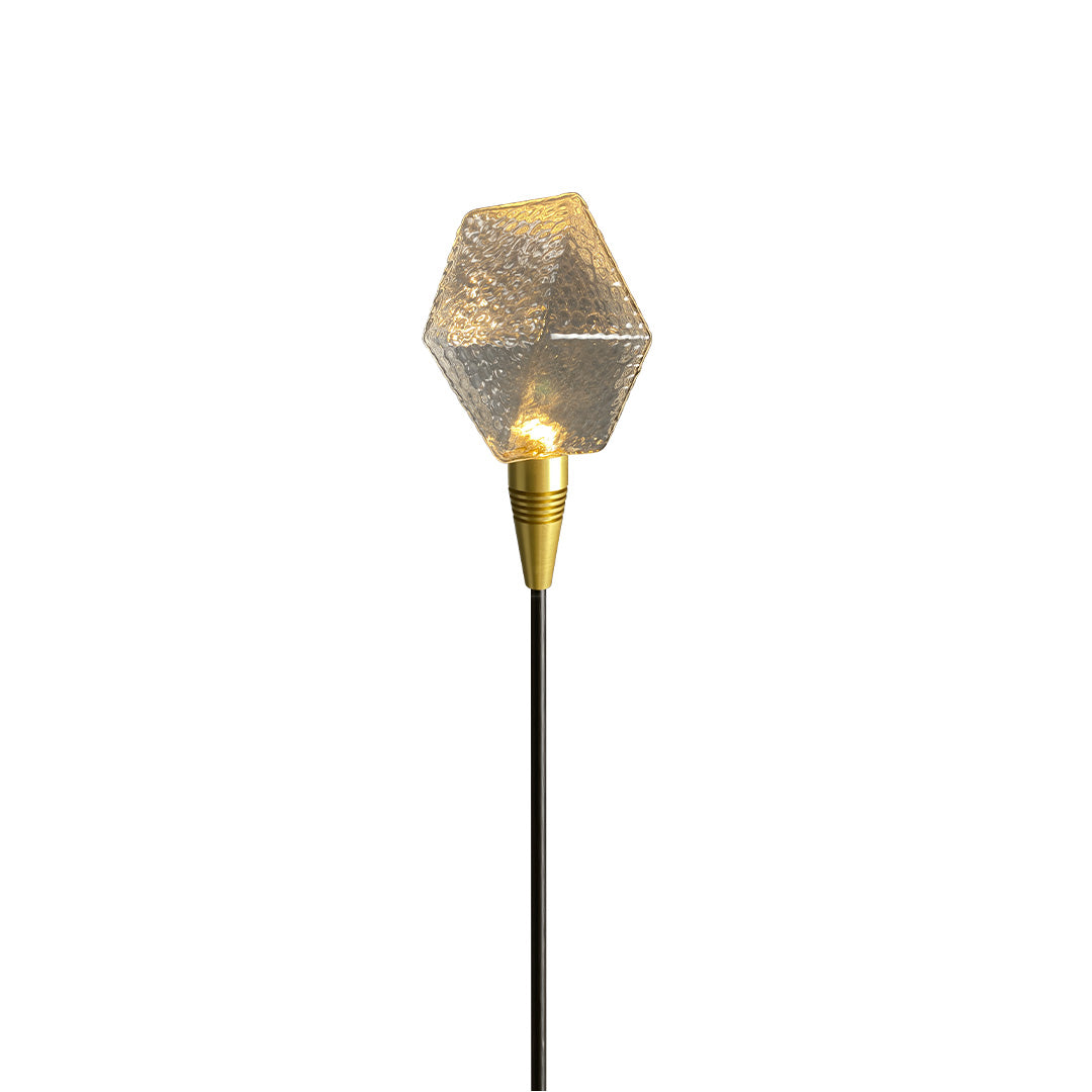Clear textured garden globe stake glowing softly, ideal for modern landscape lighting pathway arrangements.