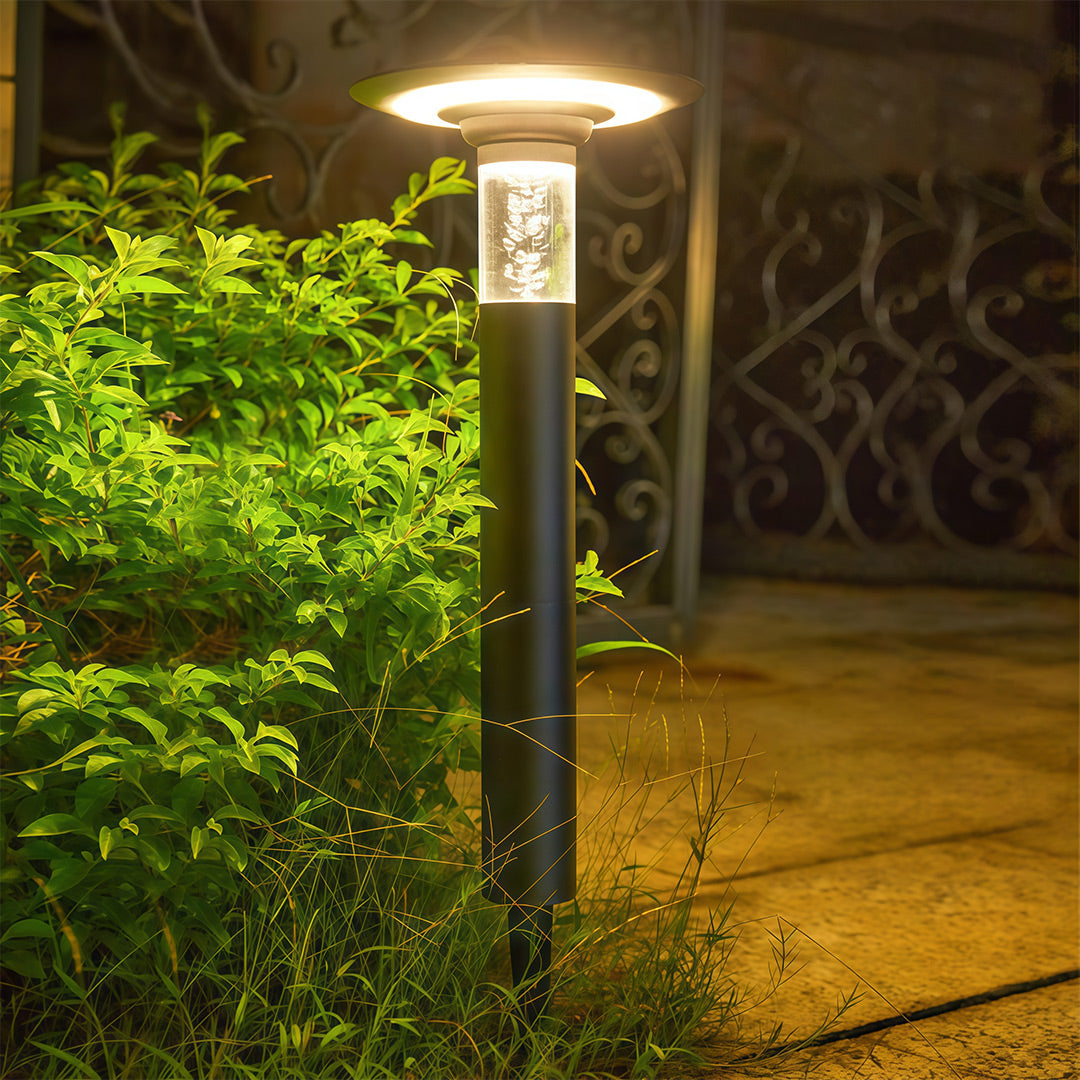 Close-up of a bubble glass outdoor path lights solar bollard glowing warmly in a garden at night.