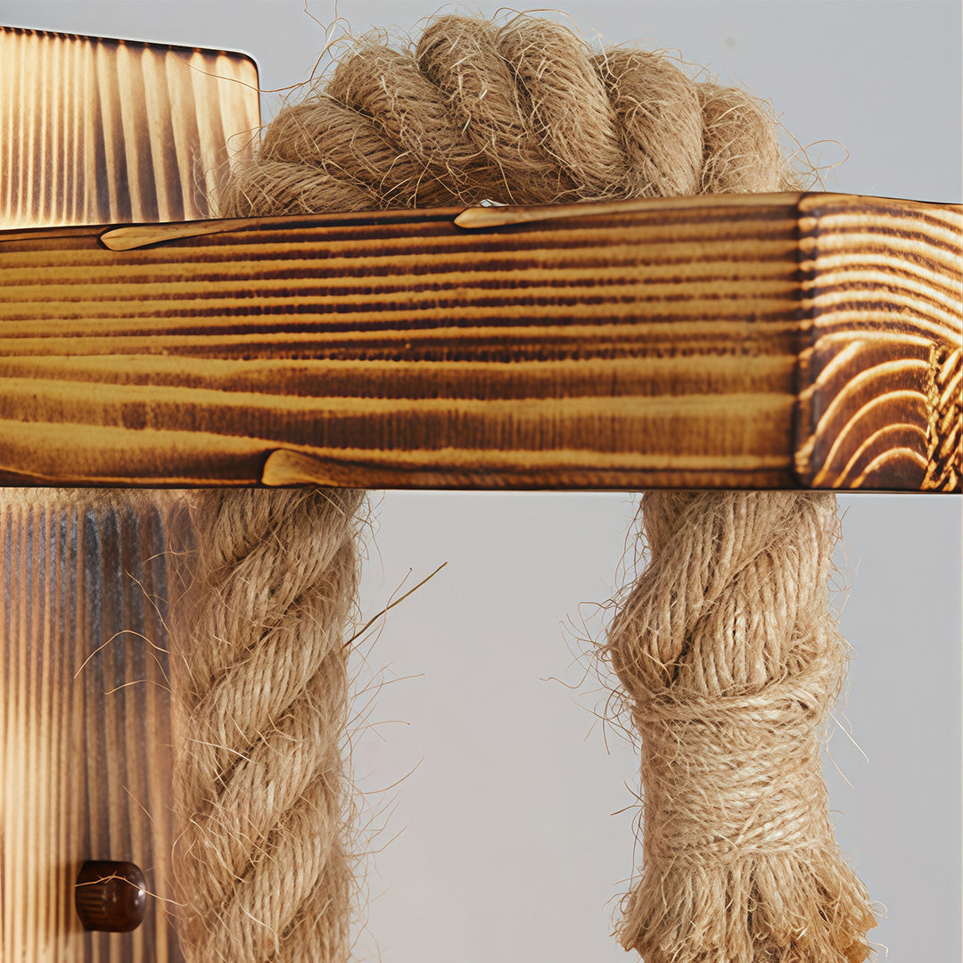 Close-up of the distressed, burnt-wood texture on the backplate of the rustic wall light, accented by the rope.