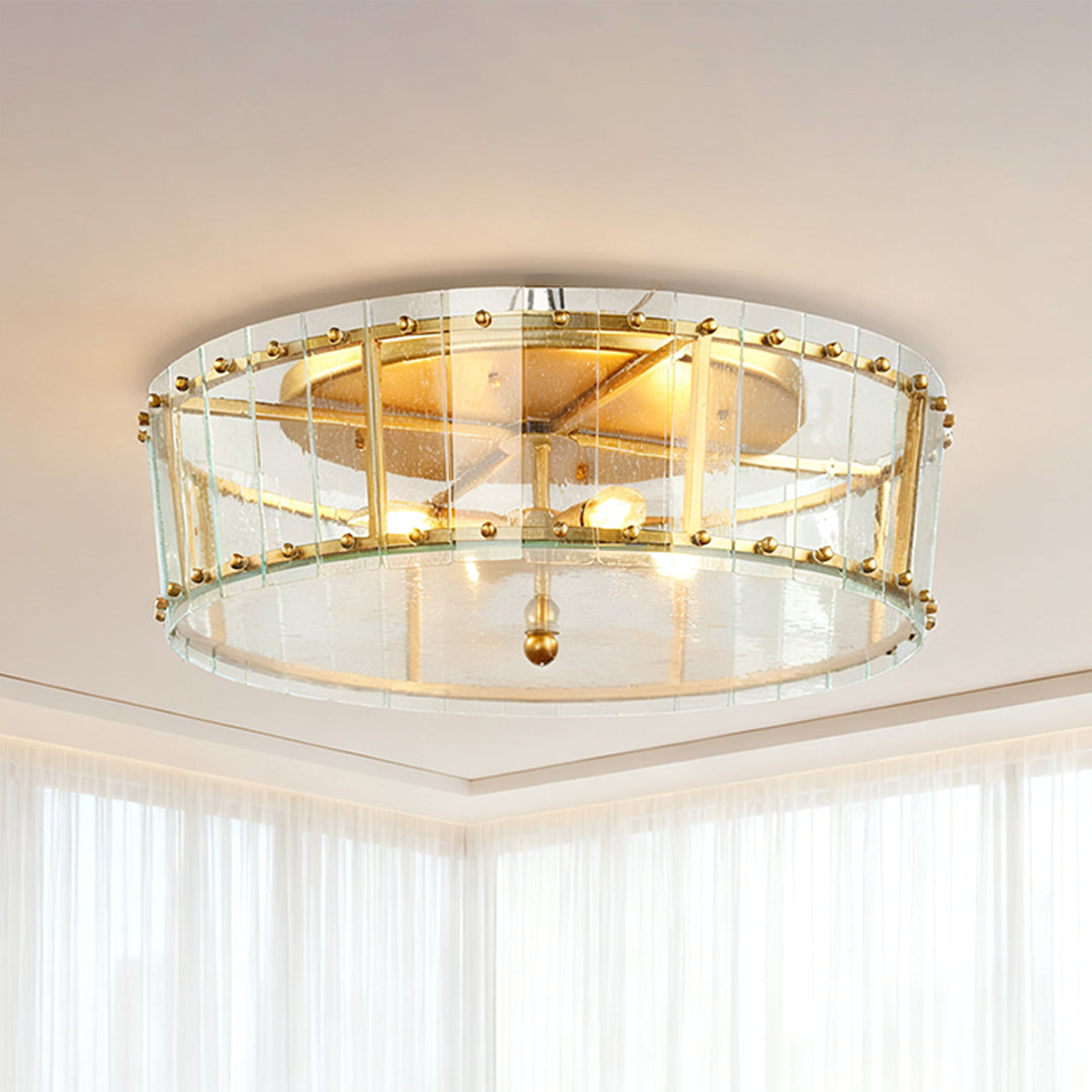Close-up view of the flush mount gold light, highlighting the exposed candelabra bulbs and the decorative crystal trim around the glass drum shade.