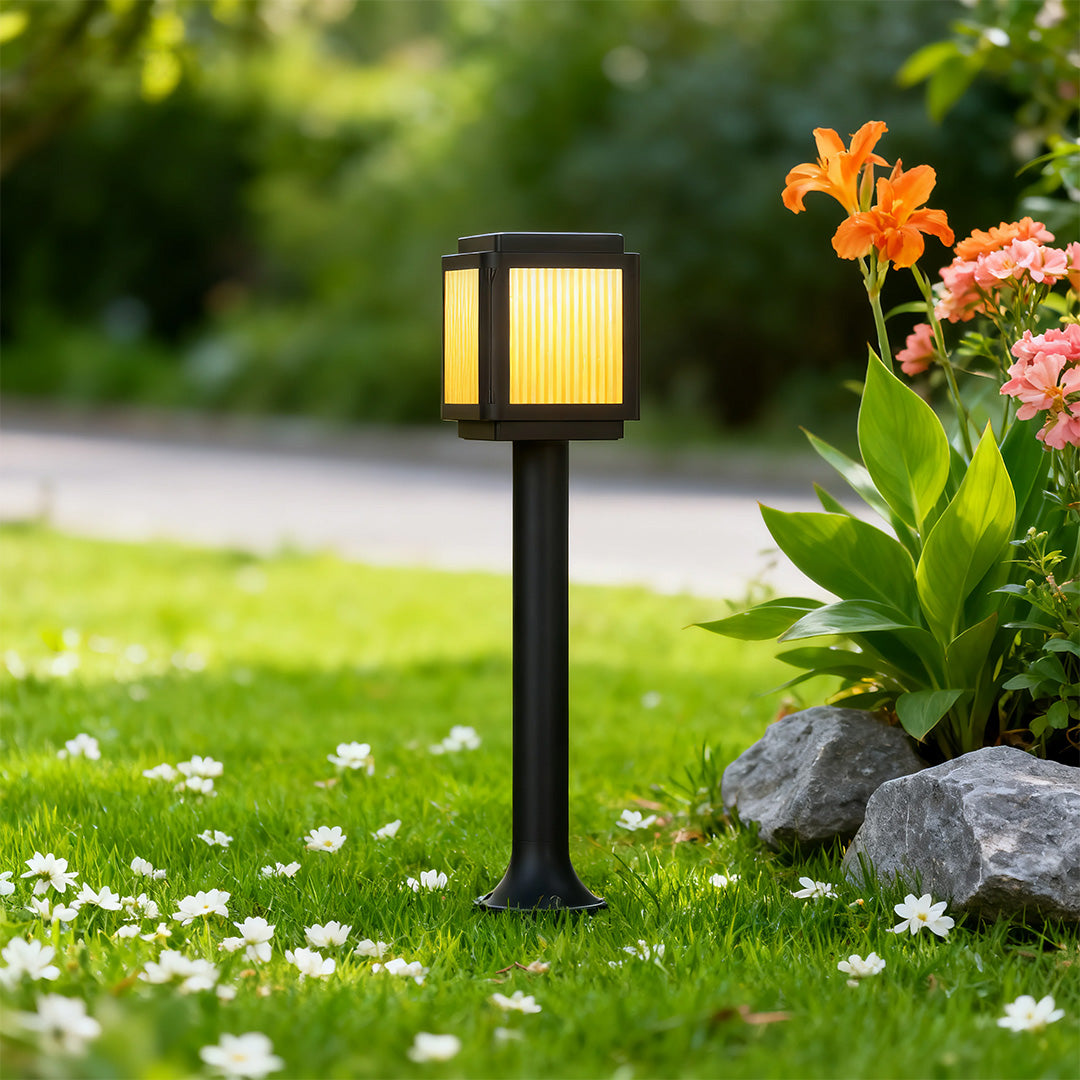 Close-up of a contemporary solar path light, highlighting the black finish and warm light source.