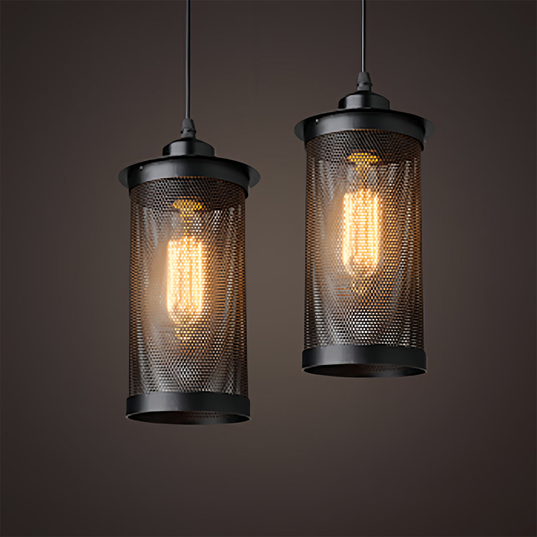 Close-up pair of cylinder retro industrial pendant lights with visible filament bulbs and black perforated metal shades.