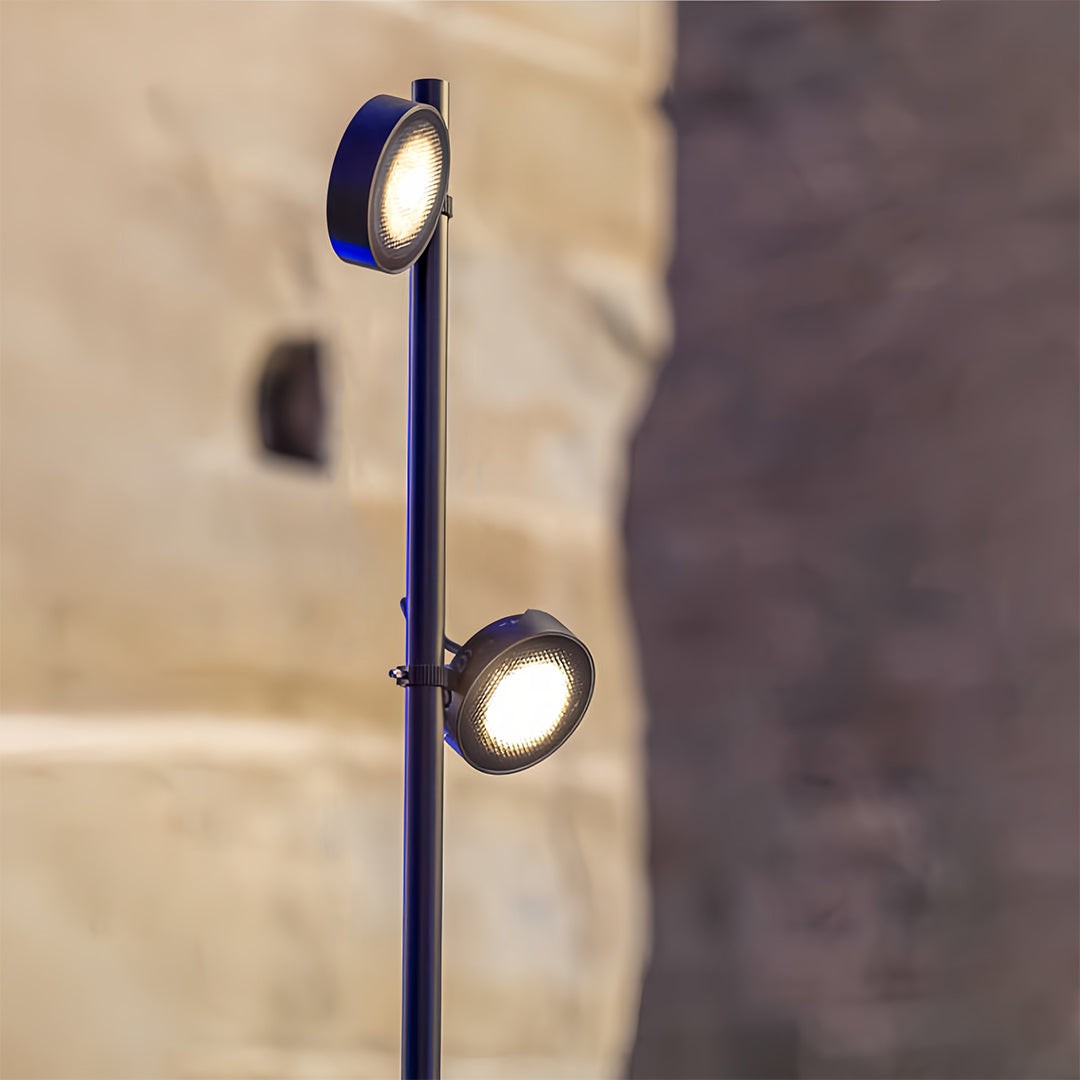 Close-up view of the black pole pathway landscape lights, showing the two directional spot heads against a textured stone wall.