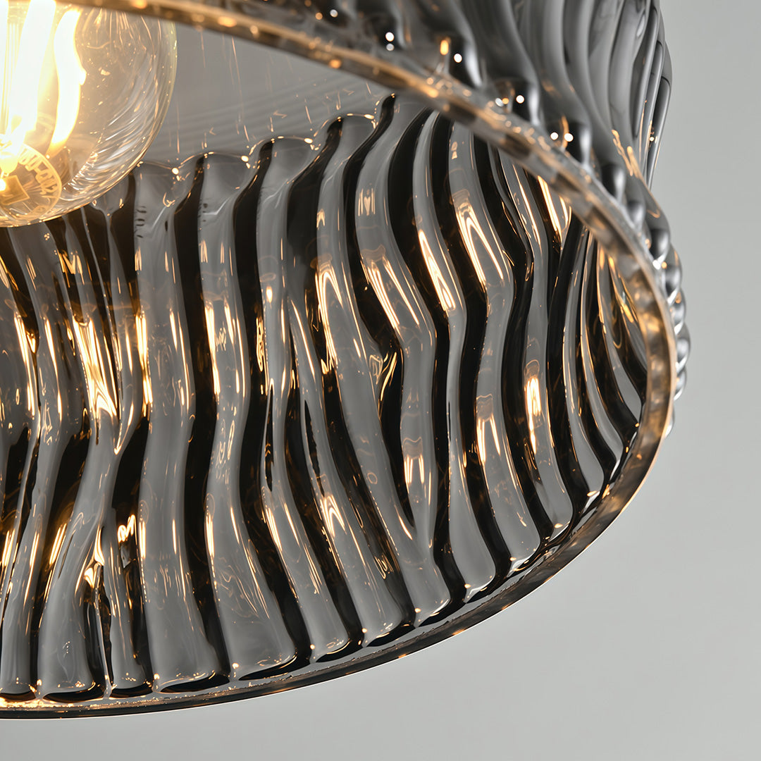 Close-up of the top of a glass drum pendant light, emphasizing the black metal frame and design.