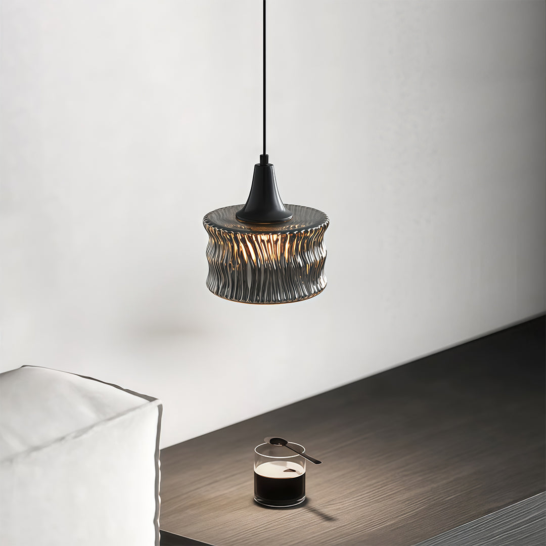 Close-up of a glass drum pendant light, highlighting the intricate textured glass and black frame.