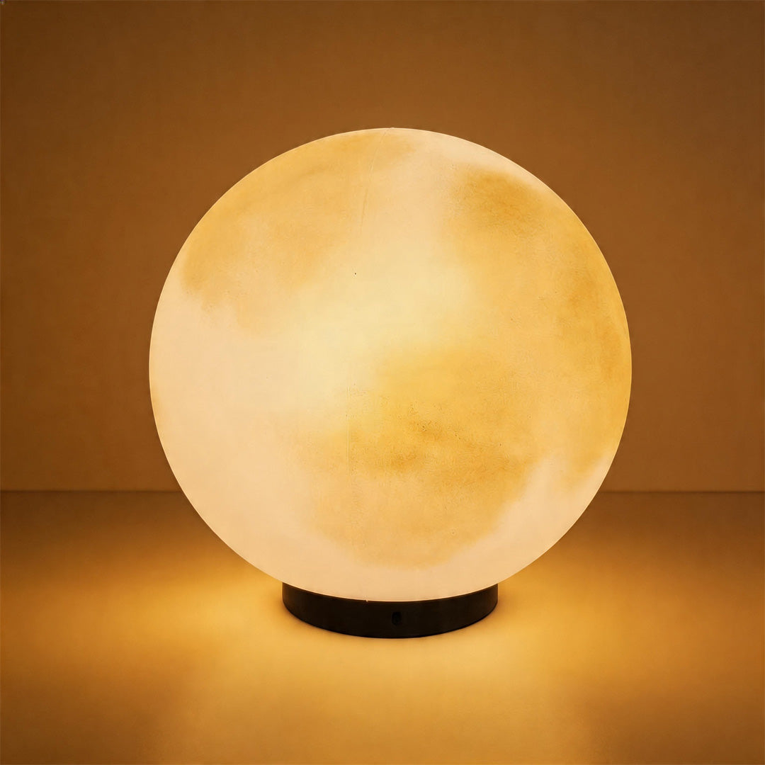 Close up detail of a glowing moon pillar light with a textured surface against a warm backdrop.