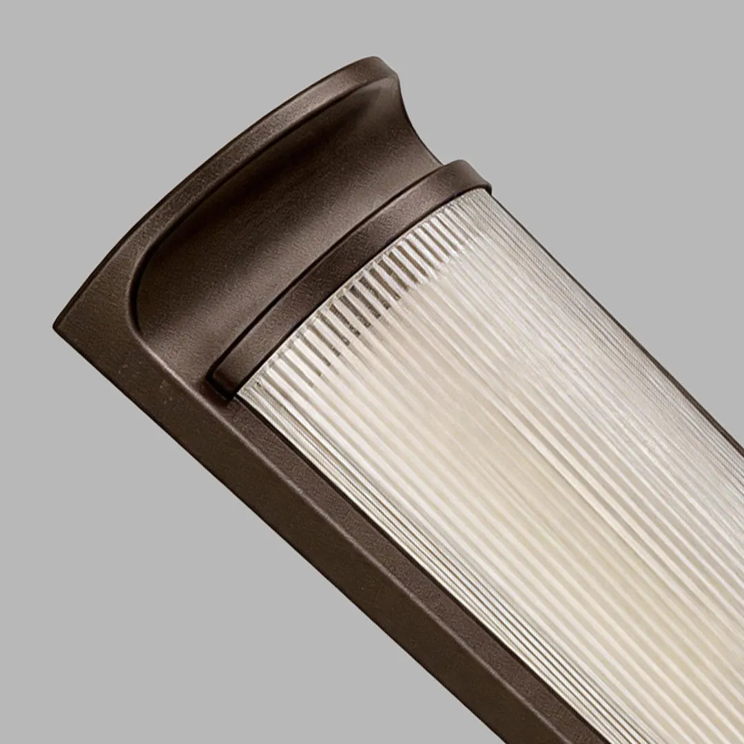 Close-up of LED outdoor wall sconces showing the bronze cap and ribbed frosted diffuser.
