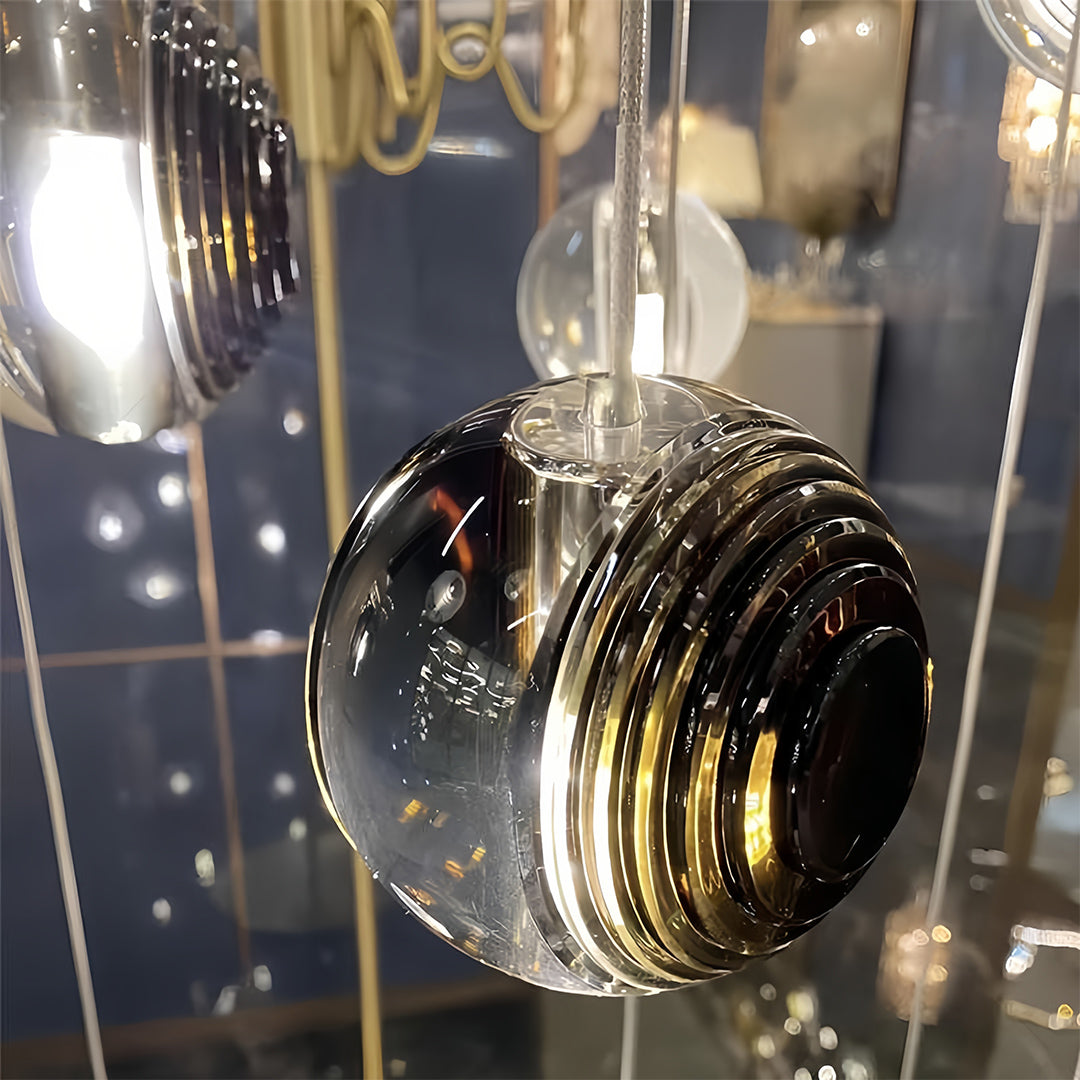 Close-up of a metal pendant light with a smoked glass sphere, emphasizing its reflective and textured surface.