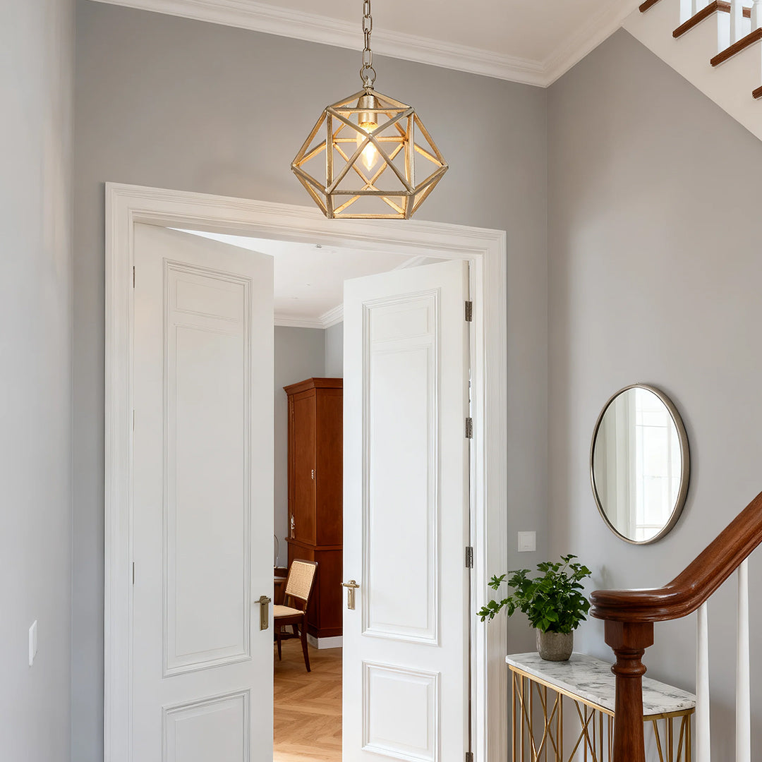 Close-up view of the small gold metal pendant light, highlighting the multifaceted brass frame and the clear glass light source.