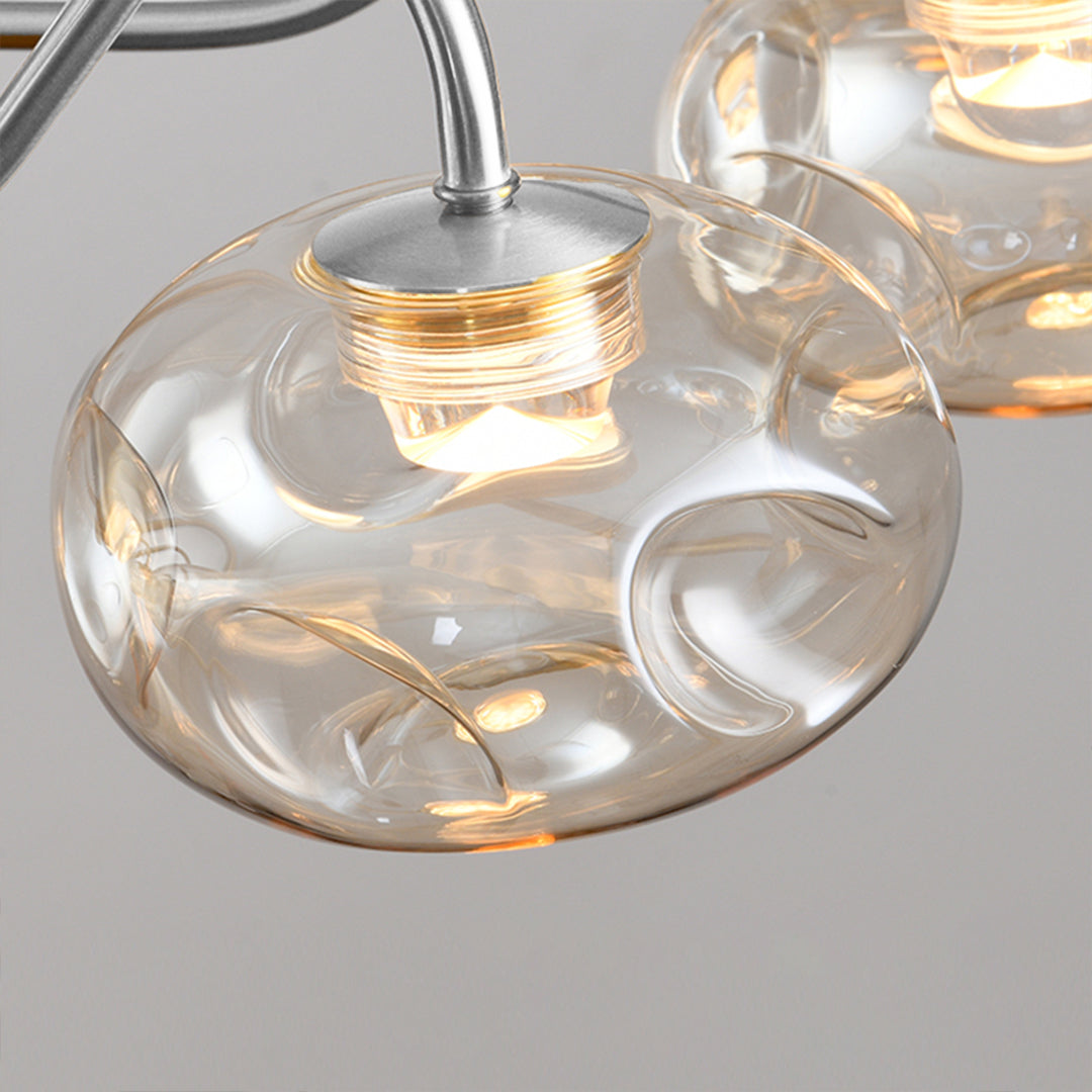 Close-up detail of art glass chandelier showing transparent glass orb with warm LED illumination