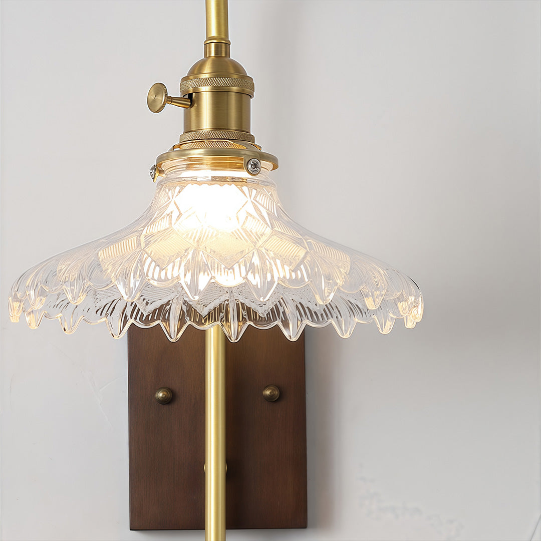 Close-up of a vintage brass glass wall lights fixture featuring a scalloped, translucent glass shade and exposed filament bulb.