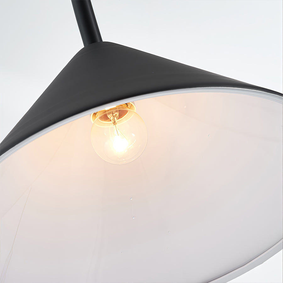 Close up detail of wall arm light showing black triangular shade with warm LED illumination and textured finish.