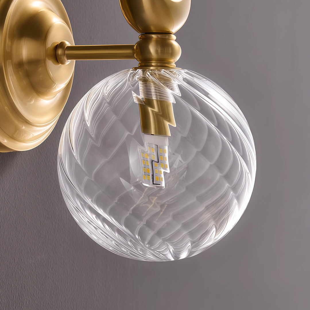 Close-up of wall mounted LED light featuring glass shade chandelier styling showing textured bubble glass and brass construction.