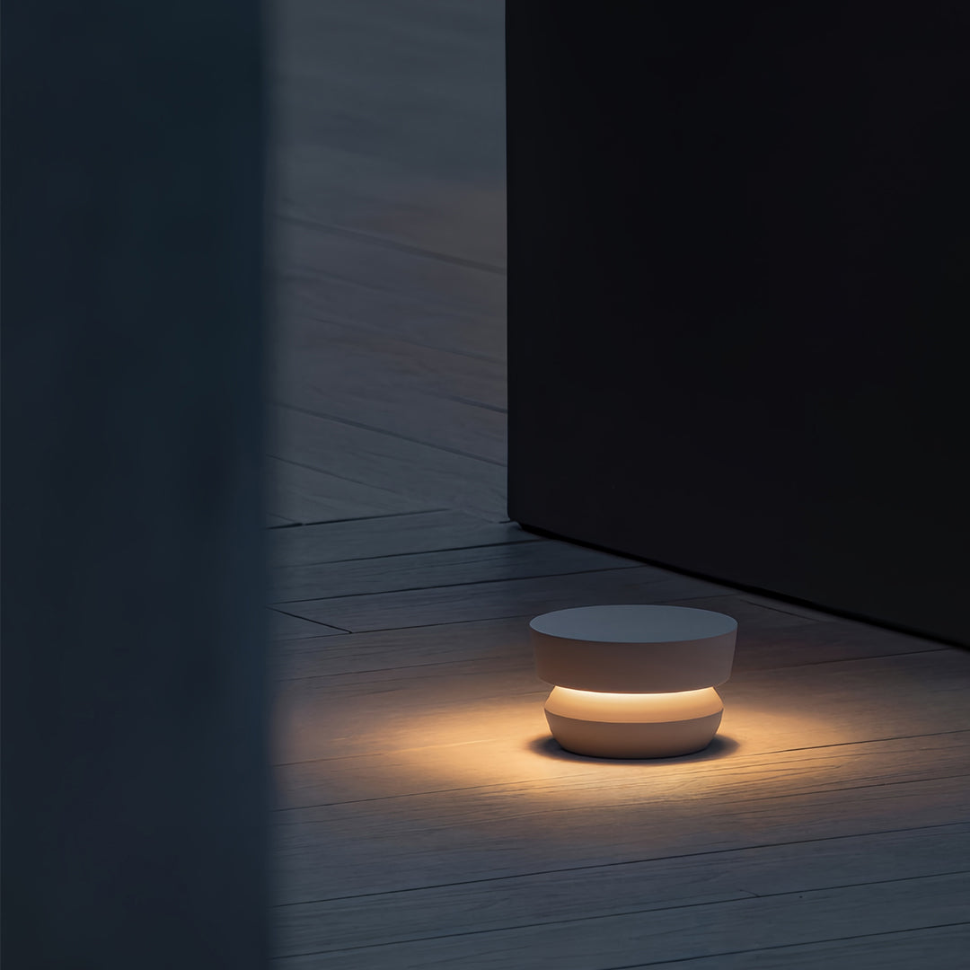 Close-up view of a single black pathway lights fixture, highlighting the warm, horizontal light band and textured dark base.