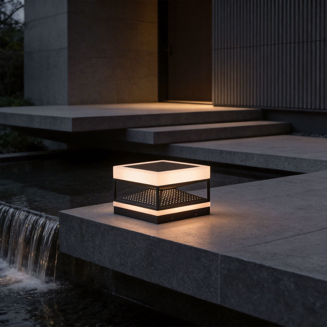 Close-up of a white pillar top light with perforated design and sleek black base.