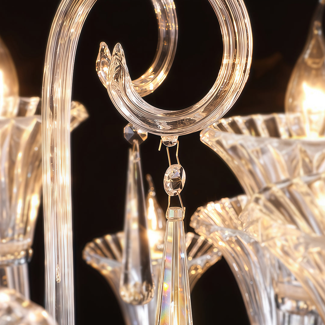 Close-up detail of art glass chandelier showing golden curved arms and crystal drops on black background.