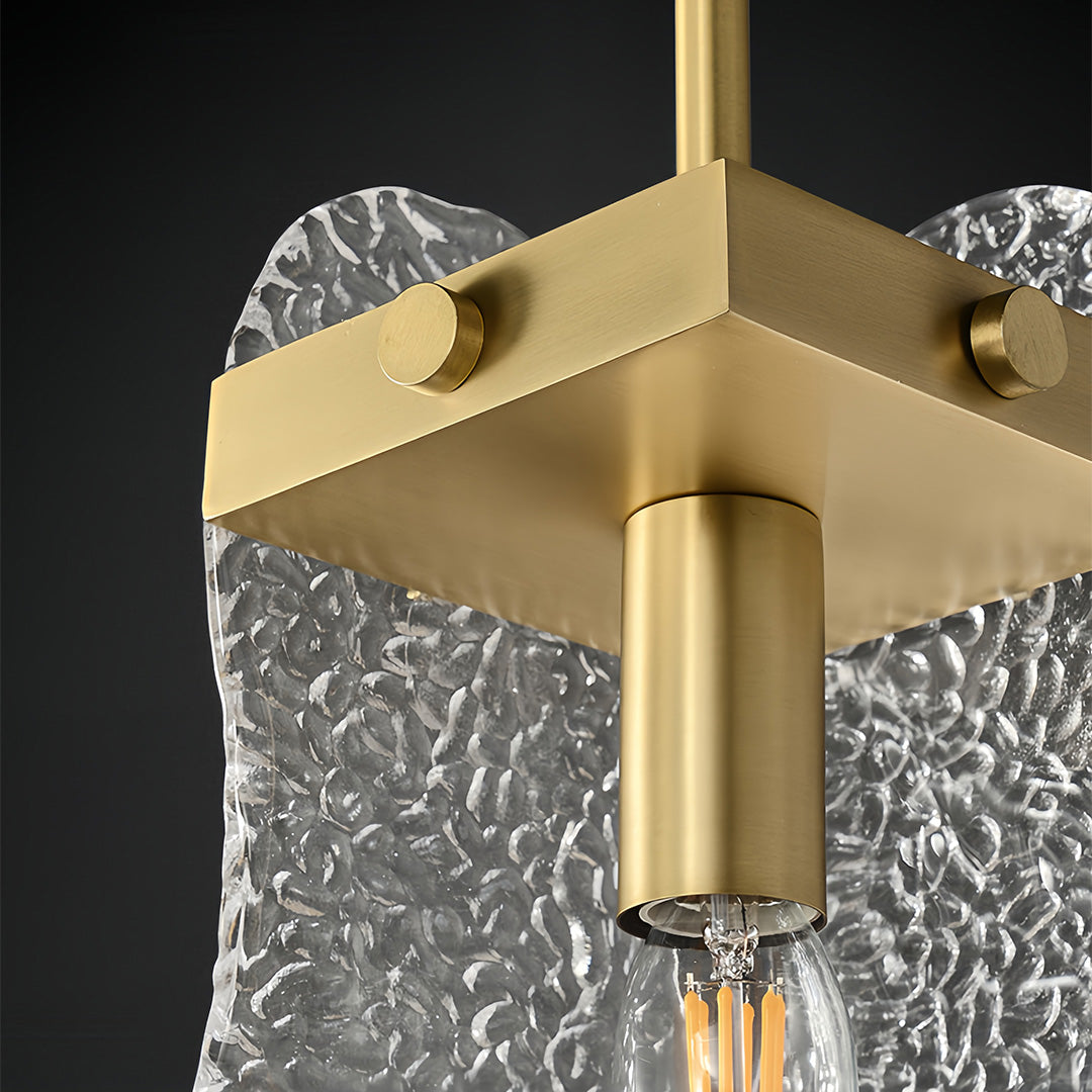 Close-up detail of brass glass pendant light showing gold canopy and textured glass construction.