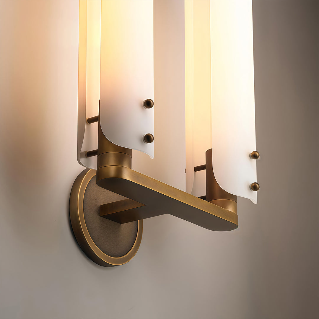 Close-up of brass wall light with glass shade revealing vintage-inspired hardware and frosted cylinder.