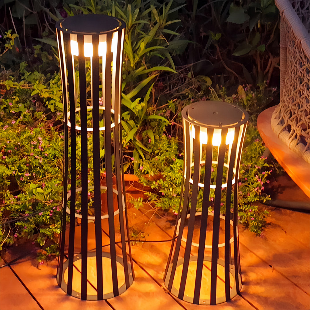 Close-up of the geometric light and shadow pattern cast by the vertical slats of the outdoor black lanterns on a stone wall.