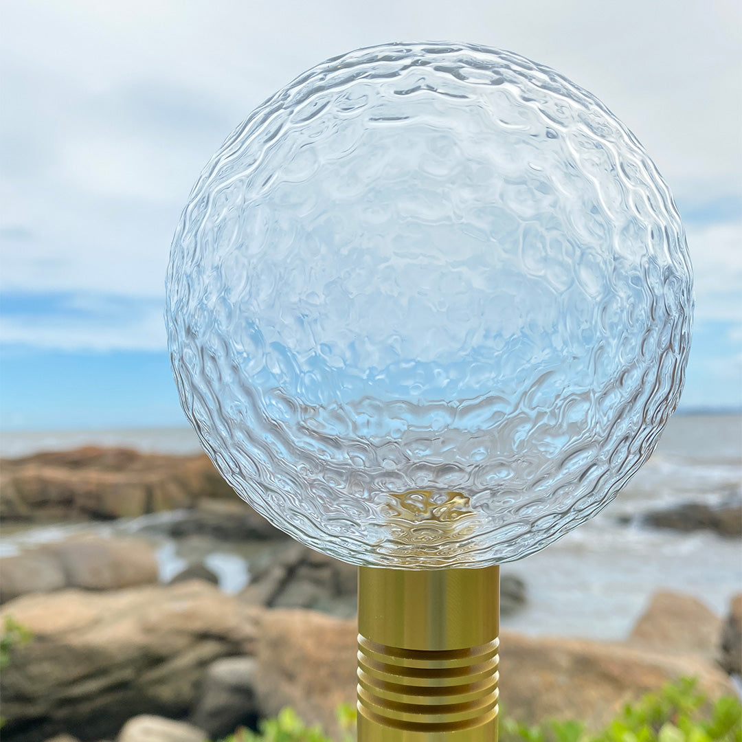 Close-up of green textured crackle-glass globe with golden base used for premium path landscape lighting.