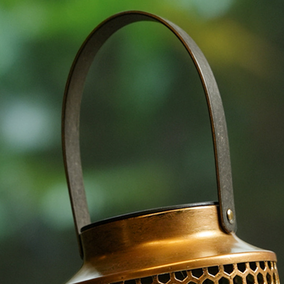 Close-up detail of the handle and upper frame of a bronze portable solar lantern.