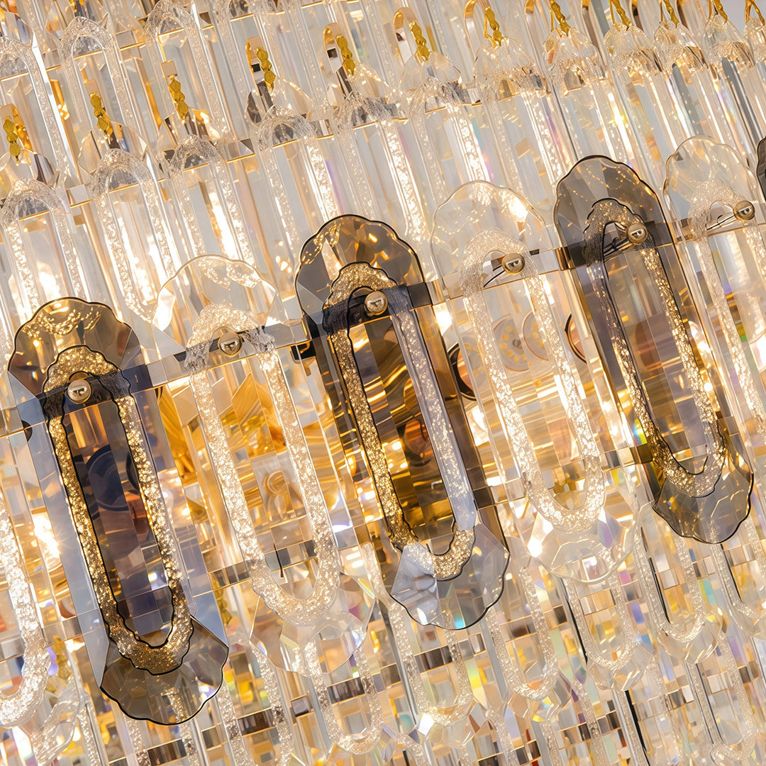 Close-up detail of large gold chandelier showing crystal strands and gold hardware construction.